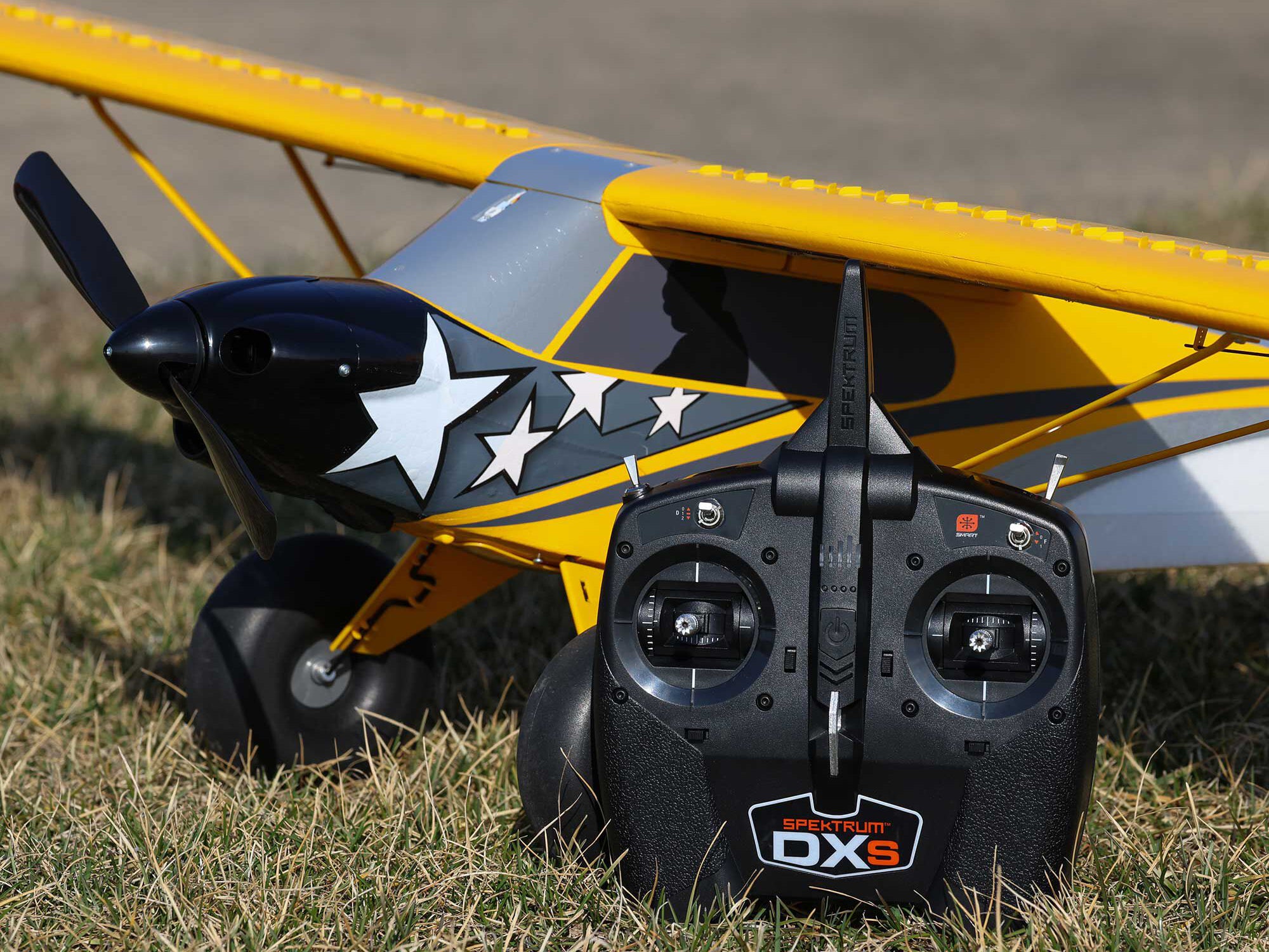 Carbon Cub S 2 Cleetus McFarland RC airplane with DXs remote control on grass.
