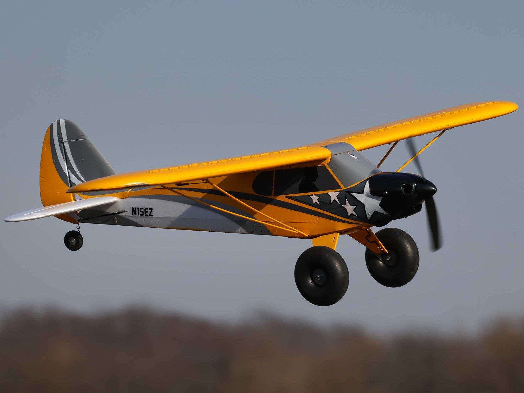 Carbon Cub S 2 Cleetus McFarland RC airplane flying against a clear sky.
