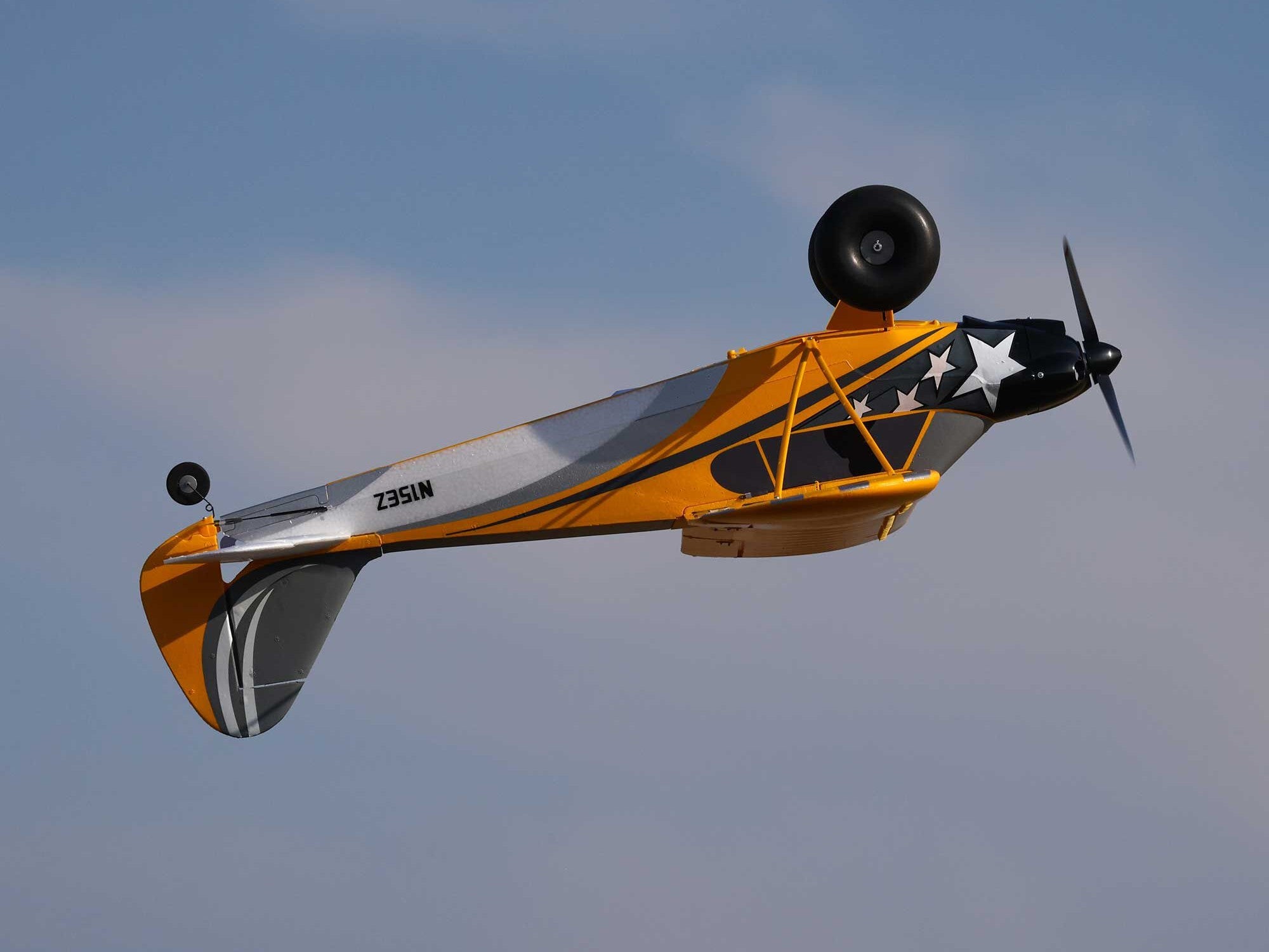 Carbon Cub S 2 Cleetus McFarland RC airplane flying upside down against a blue sky.