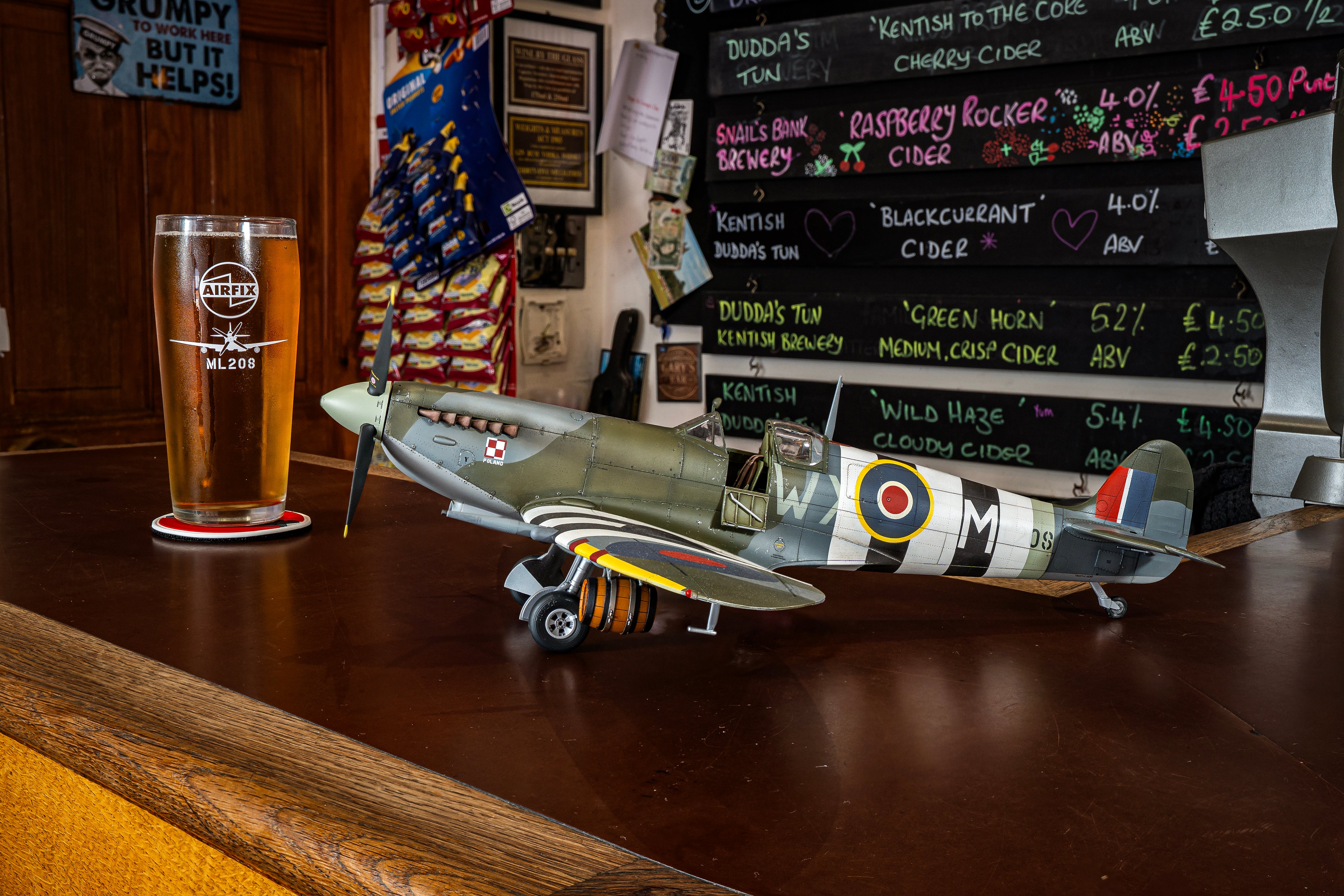 Model airplane on a bar counter with a pint glass and menu board in the background