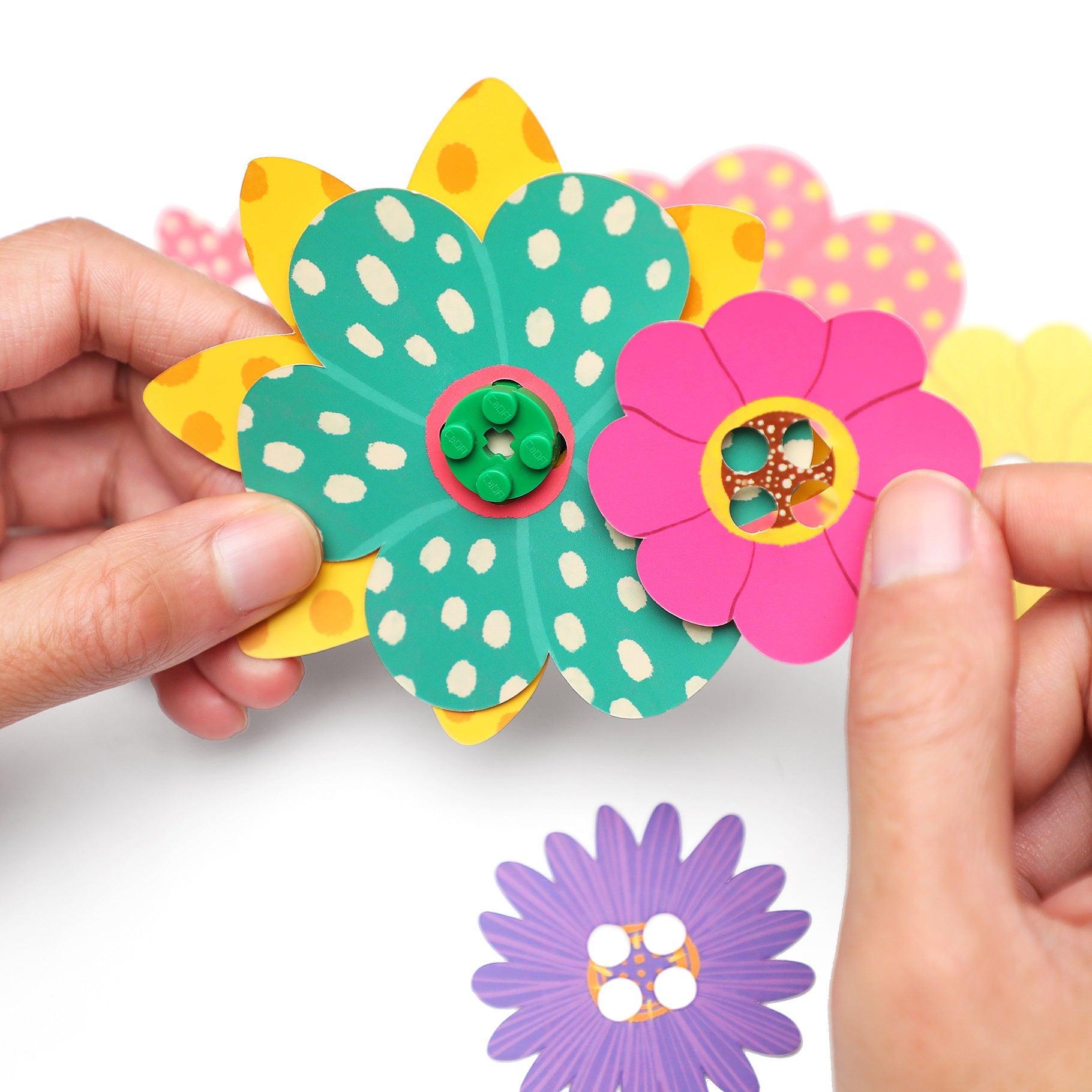 Hands assembling colorful flowers from the CaDA Flower Garden model C71022W, showcasing creativity and vibrant designs.