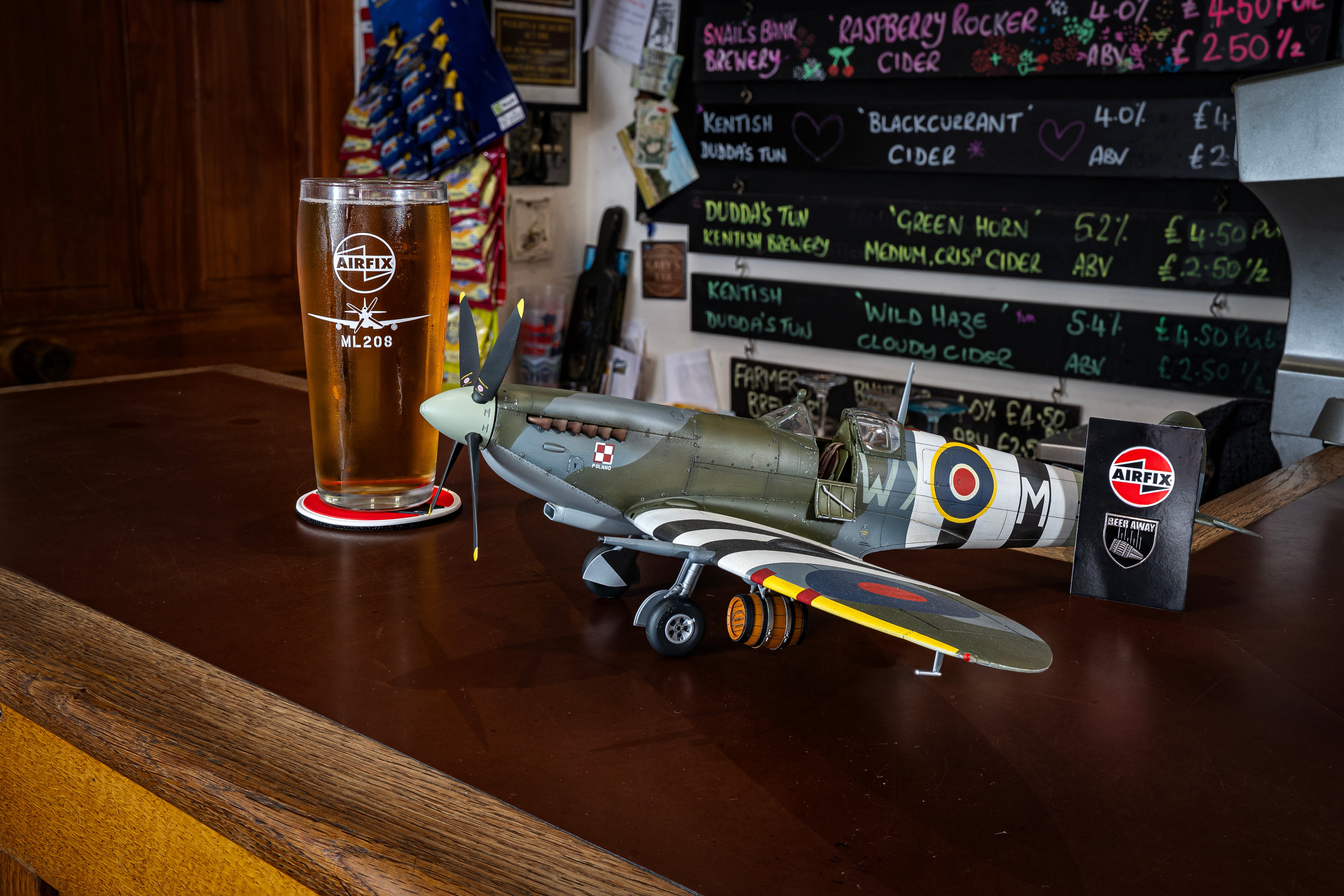 Model airplane on a bar counter with a pint glass and menu board in the background