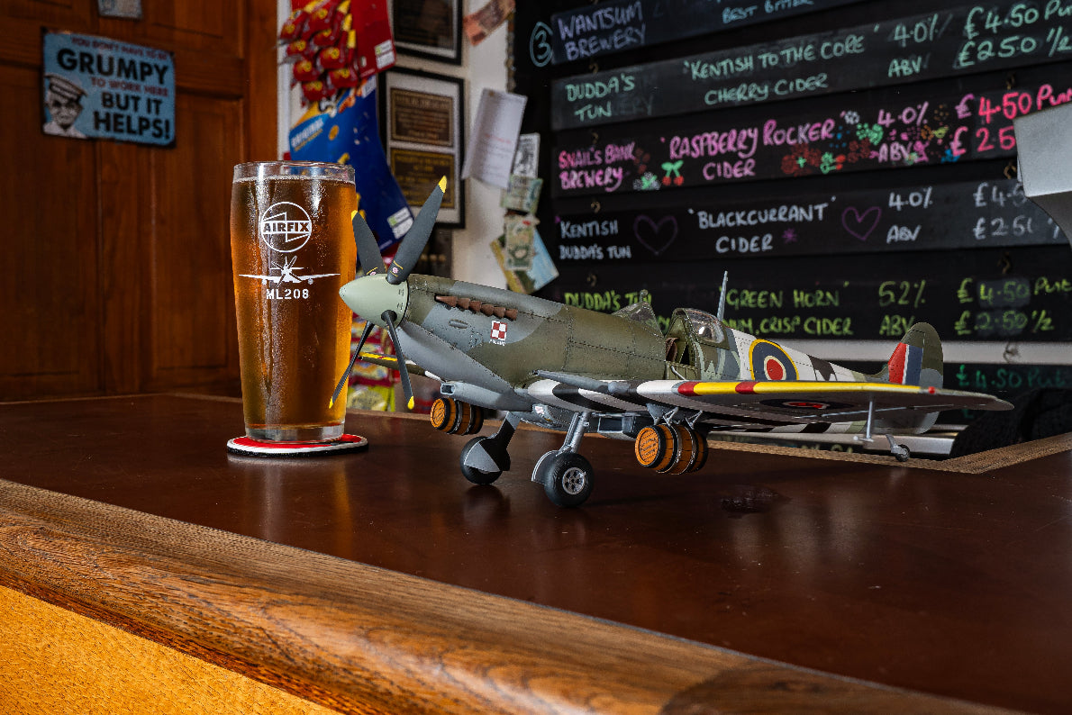 Pint glass on a bar with a model airplane and a menu in the background