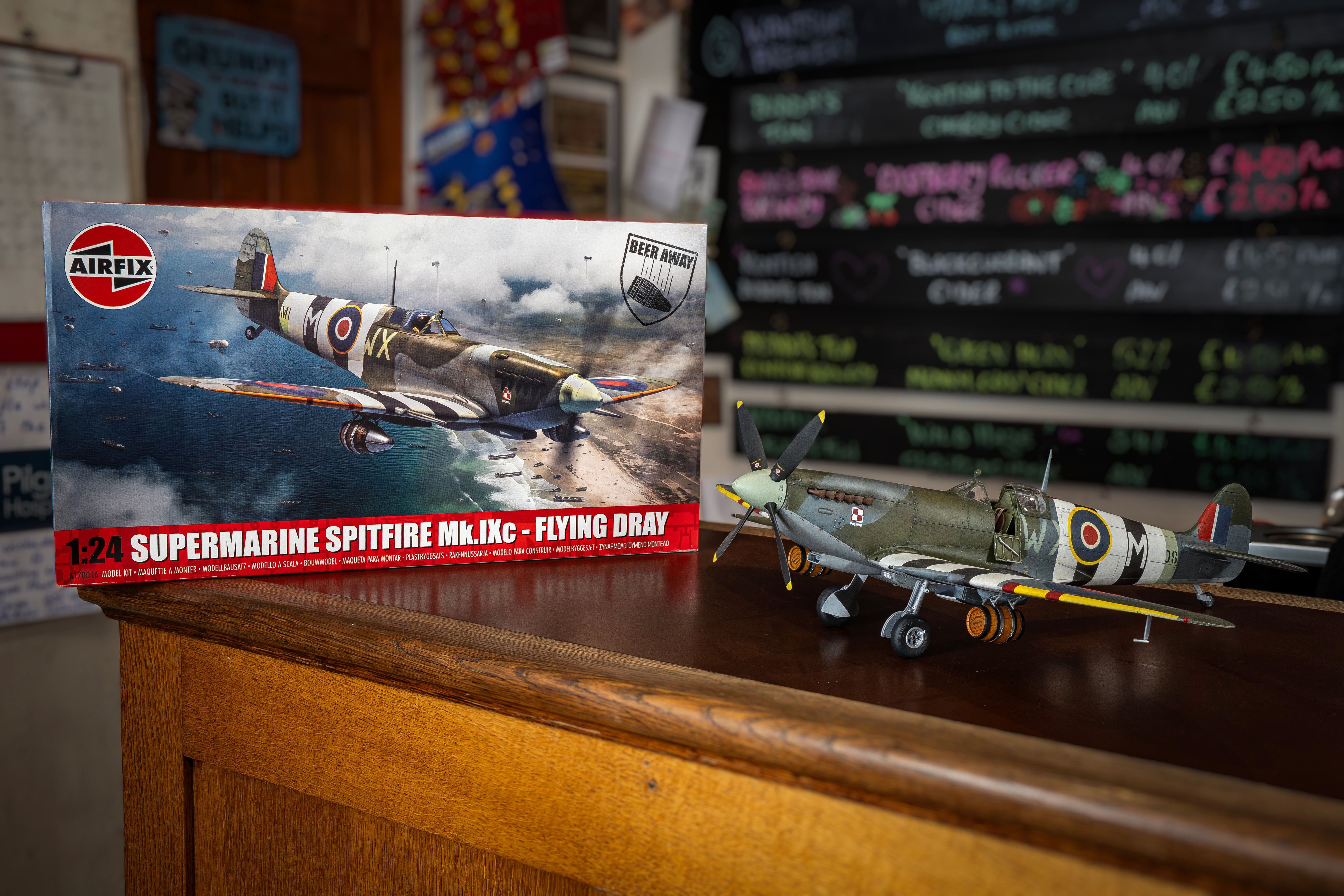 Model Supermarine Spitfire Mk.IX with Airfix packaging on a wooden surface.