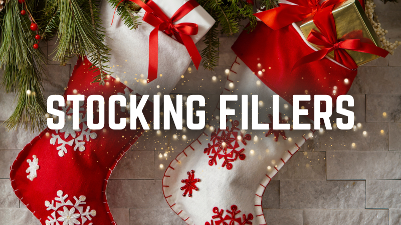 Red and white stocking fillers with Christmas decorations on a stone wall background.