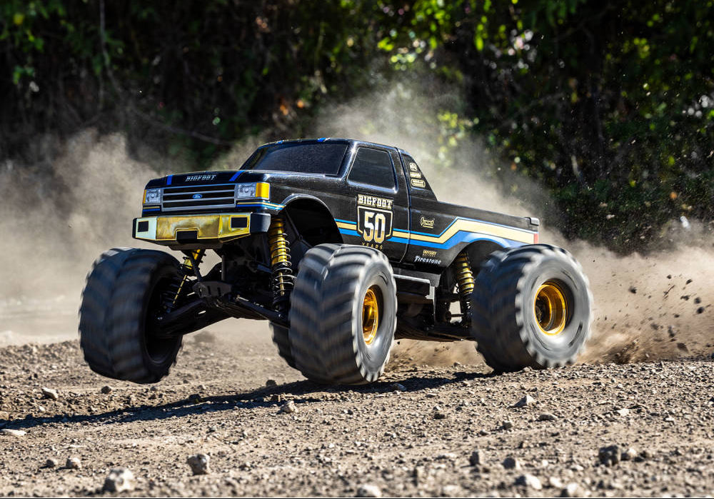 Monster truck on a dirt track with trees in the background