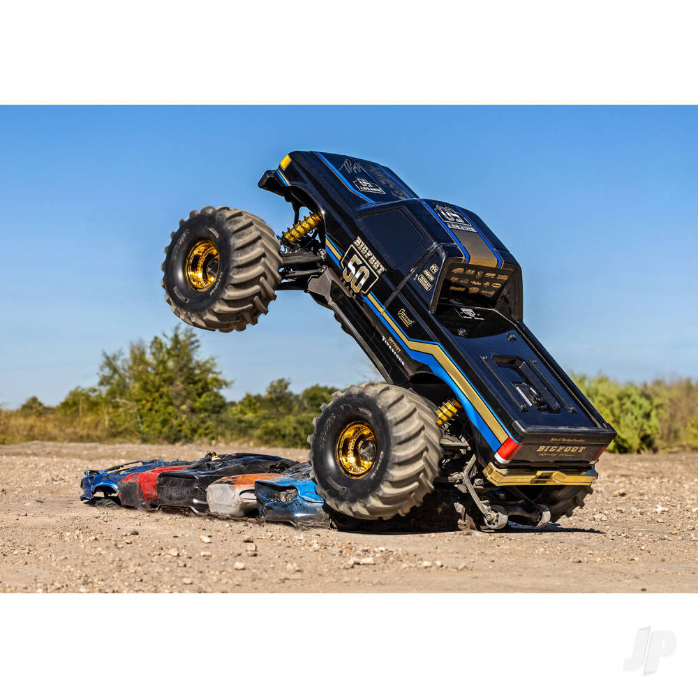 Monster truck performing a flip in an outdoor setting with a clear blue sky.