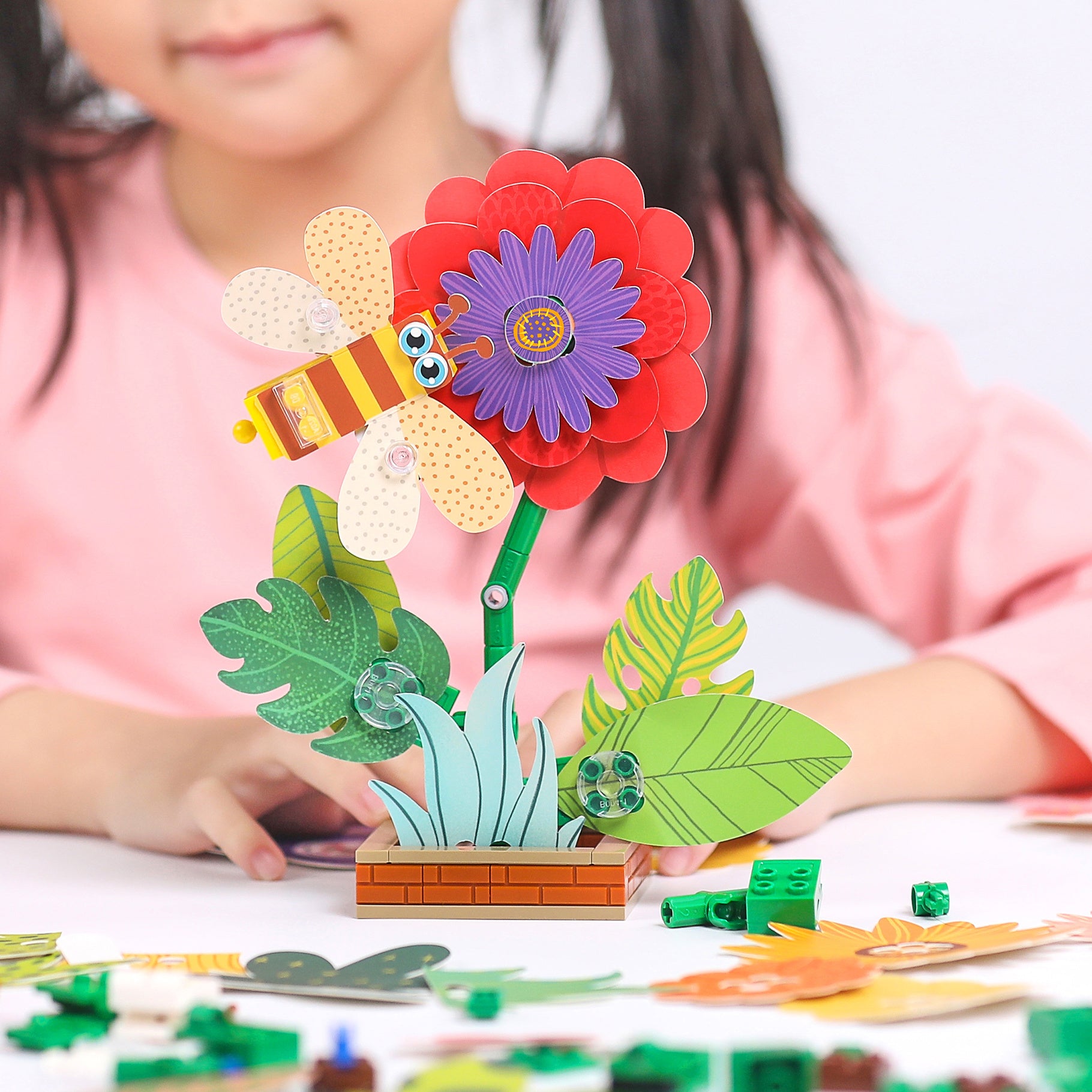 A child building the CaDA Flower Garden model (C71022W) with vibrant flower and leaves.